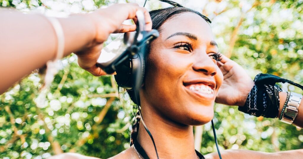 adult with braces putting on headphones to listen to a podcast about summer dental hygiene